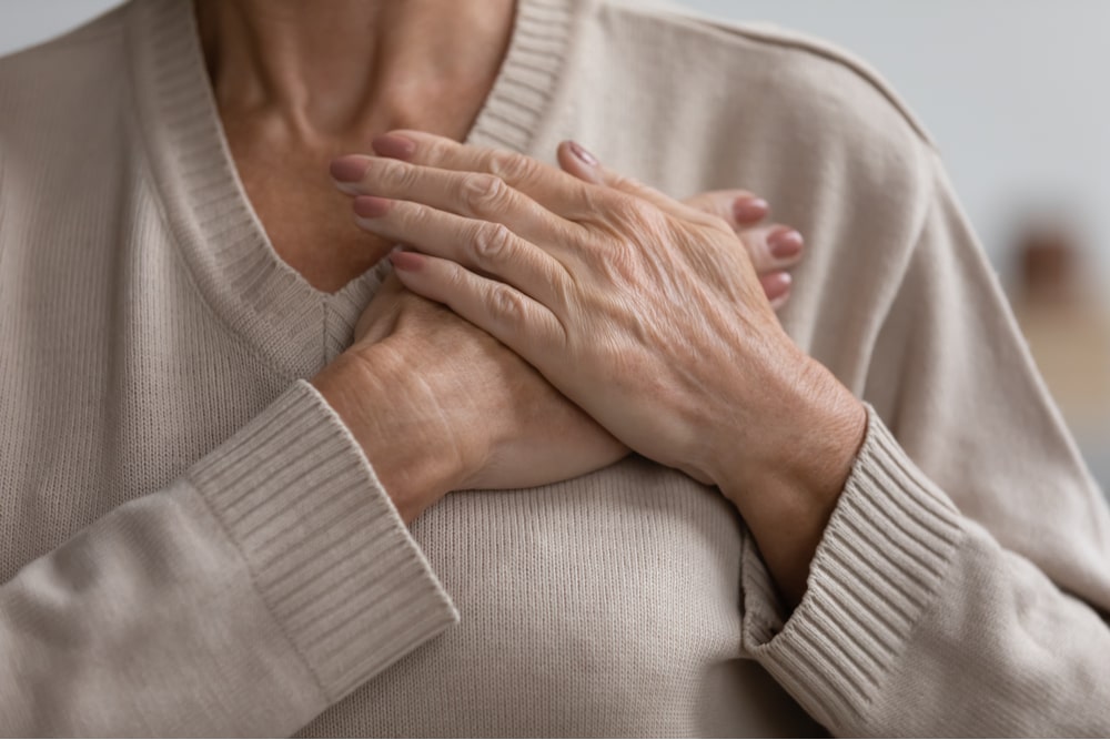senior woman keeping hands on chest